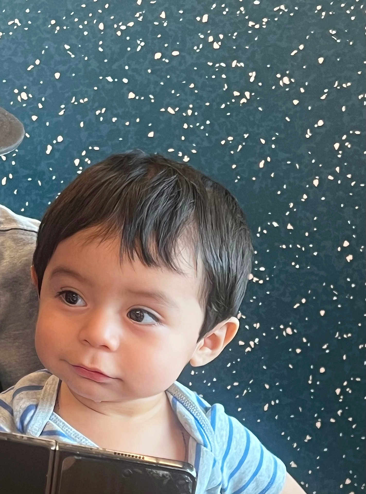 Juan joined the competition — help win amazing prizes! toddler, child, face, portrait, curious, indoor, striped_shirt, black_hair, big_eyes, expression, person, young_child, holding_object, closeup, cute, innocent, skin, head, background, blue