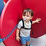 toddler, child, pacifier, harness, blue_shorts, blue_crocs, red_heart, playground, outdoor, person, child_wearing_pacifier, footwear, clothing, toy, plastic, hand, face, hair, standing, curly_cord