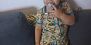 Michael is registered to the contest to win money with this photo: toddler, child, pacifier, romper, monkey_print, couch, living_room, smile, standing, indoor, furniture, can, shorts, clothing, person, happy, hair, face, playful, cute