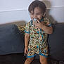 toddler, child, pacifier, romper, monkey_print, couch, living_room, smile, standing, indoor, furniture, can, shorts, clothing, person, happy, hair, face, playful, cute