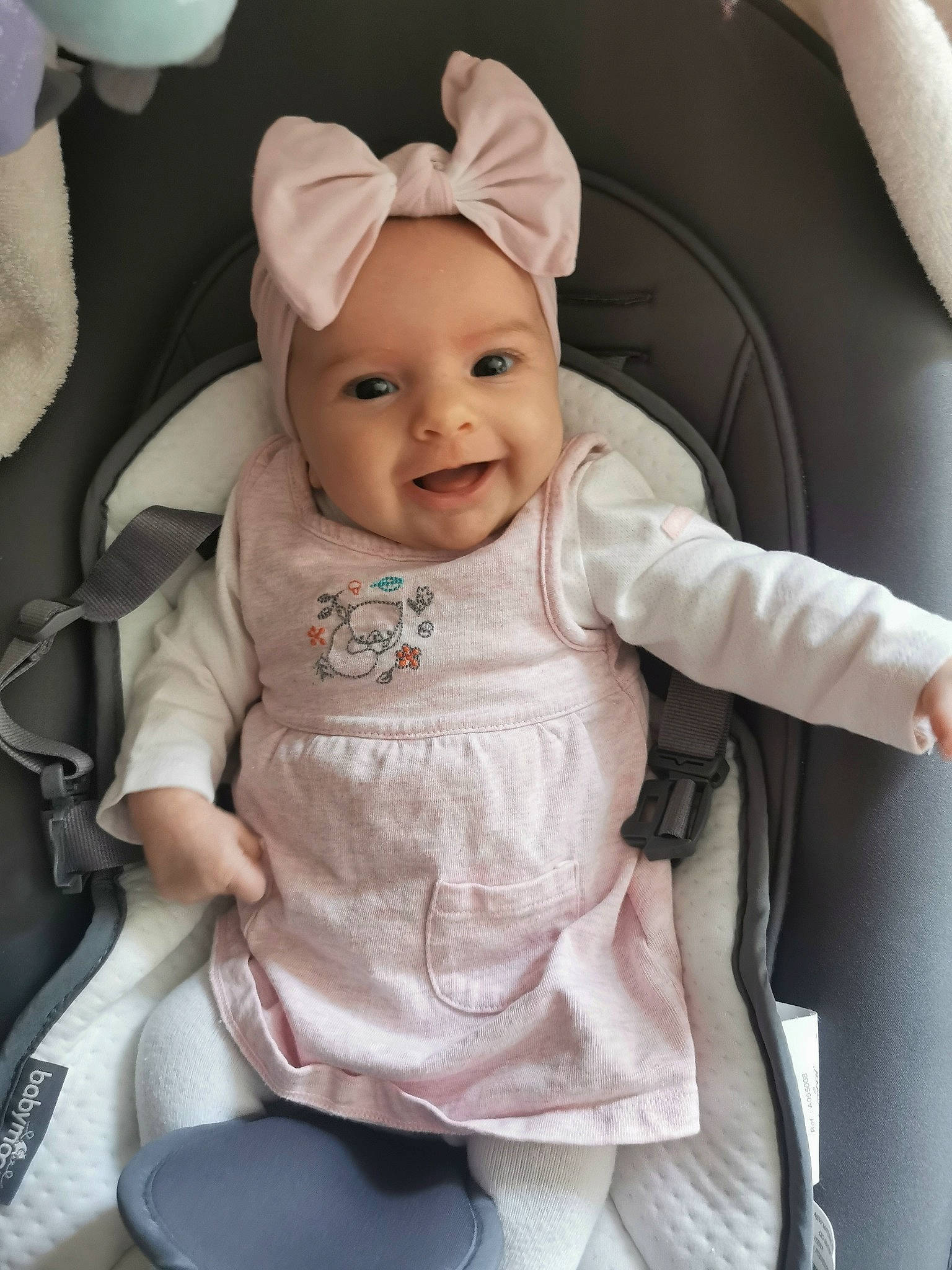 Philaé participe au concours pour gagner de l'argent avec cette photo : baby, baby_products, baby_toddler_clothing, car_seat, cheek, child, comfort, fashion_accessory, happy, head, headwear, magenta, outerwear, person, pink, sitting, skin, sleeve, smile, textile