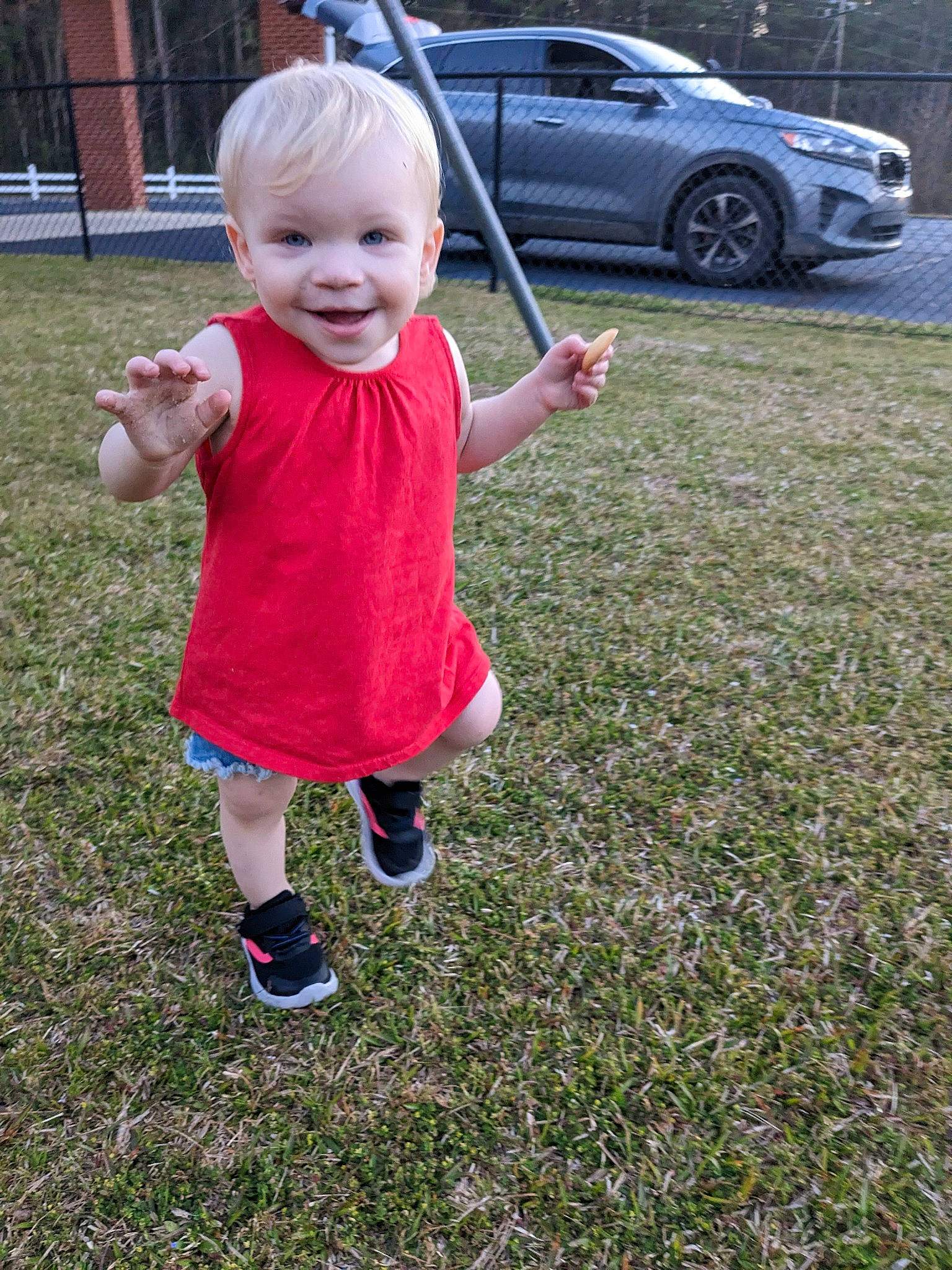 Amira is registered to the contest to win money with this photo: alloy_wheel, automotive_exterior, automotive_tire, baby, baby_toddler_clothing, car, fun, grass, happy, joy, leg, motor_vehicle, people_in_nature, person, plant, rim, smile, tire, toddler, vehicle