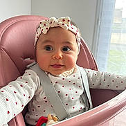 Adèle participe au concours pour gagner de l'argent avec cette photo : baby, child, high_chair, headband, heart_pattern, pink, seatbelt, toy, indoor, curious, cute, infant, clothing, person, face, cheeks, long_sleeve, window, daylight, expression