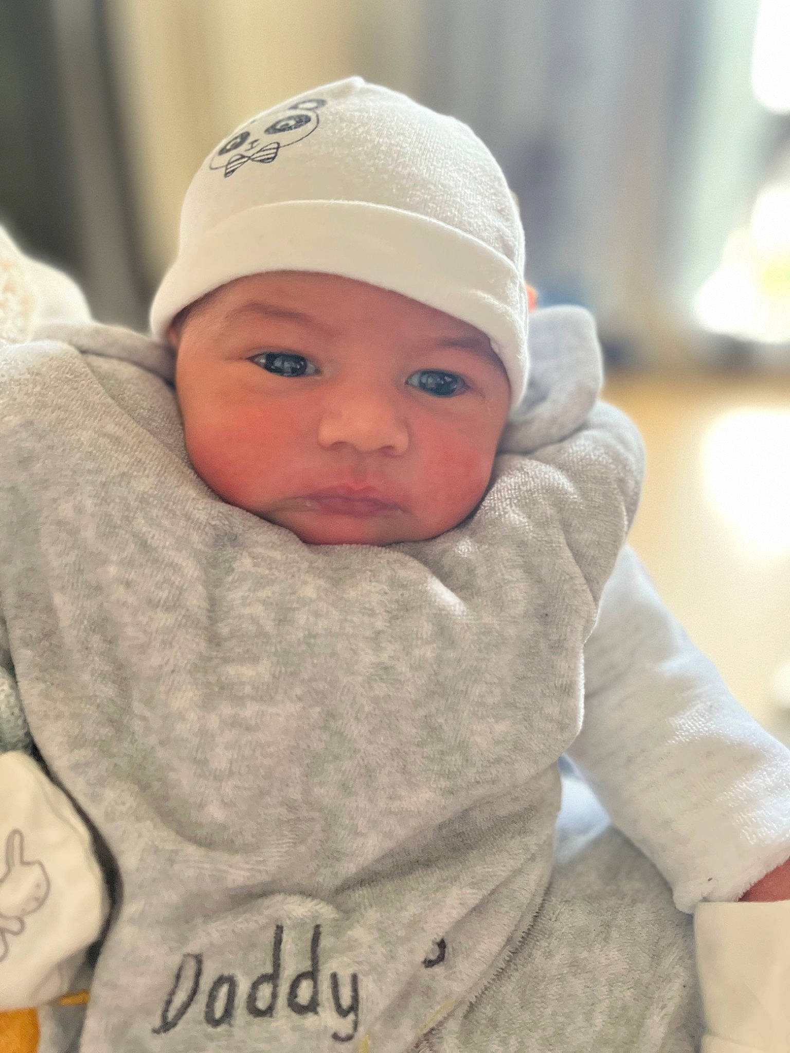 Maylan participe au concours pour gagner de l'argent avec cette photo : baby, baby_toddler_clothing, beanie, cap, cheek, child, chin, comfort, eyebrow, face, facial_expression, happy, headgear, headwear, lip, outerwear, person, portrait_photography, sitting, skin