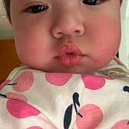 May is registered to the contest to win money with this photo: baby, child, face, pout, cheeks, close_up, indoor, clothing, pattern, pink, white, person, infant, cute, soft_light, portrait, young, expression, cherry_pattern, wearing