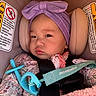 baby, blanket, bow, car_seat, close_up, cute, earring, floral_clothing, harness, headband, infant, pacifier, pacifier_strap, pink, portrait, safety_warning, sleepy, sticker, teal, toy