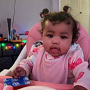 Ivy joined the competition — help win amazing prizes! baby, child, highchair, bib, pink, pigtails, curly_hair, face, eyes, mouth, toy, tray, indoor, living_room, television, decorative_lights, furniture, hand, clothing, feeding