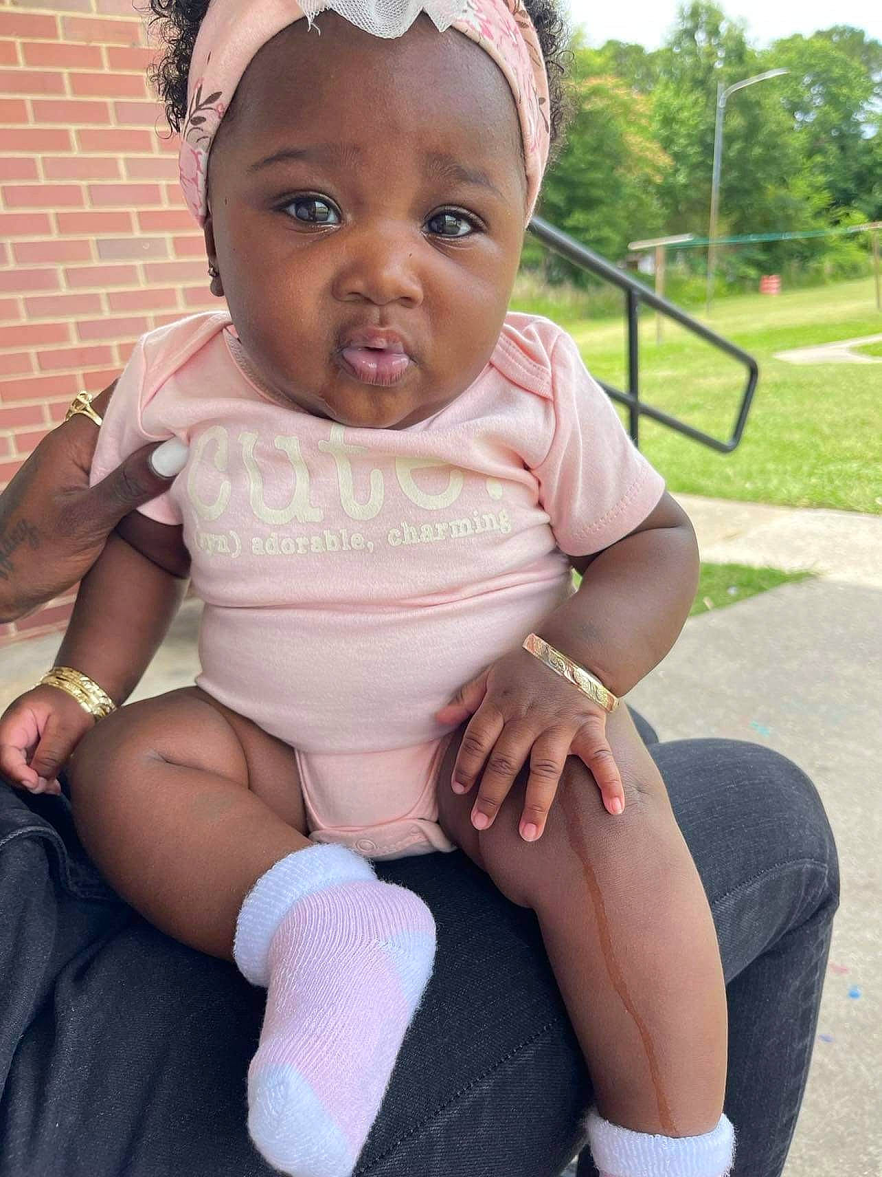 Tailoni is registered to the contest to win money with this photo: baby, baby_toddler_clothing, eye, face, finger, grass, hairstyle, happy, head, human_body, knee, leg, lip, neck, person, pink, plant, skin, thigh, toddler