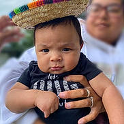 Jefe Noel joined the competition — help win amazing prizes! baby, child, sombrero, hat, hand, adult, person, face, black_shirt, outdoor, portrait, expression, holding, rings, glasses, blurred_background, skin, cute, serious, clothing