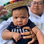 baby, child, sombrero, hat, hand, adult, person, face, black_shirt, outdoor, portrait, expression, holding, rings, glasses, blurred_background, skin, cute, serious, clothing