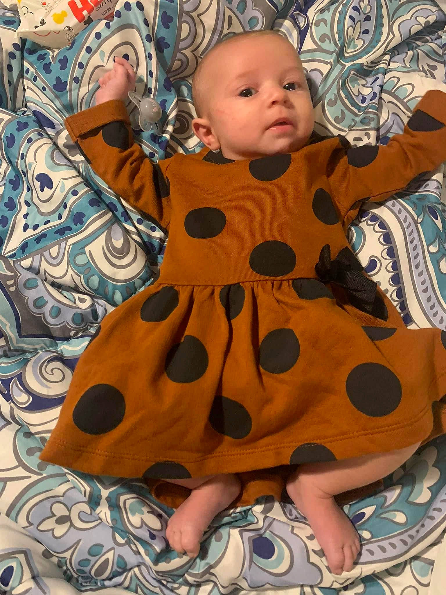 Astrid joined the competition — help win amazing prizes! baby, baby_toddler_clothing, cheek, child, dress, eye, face, fawn, head, human_body, iris, linens, nose, outerwear, pattern, peach, person, sitting, skin, sleeve