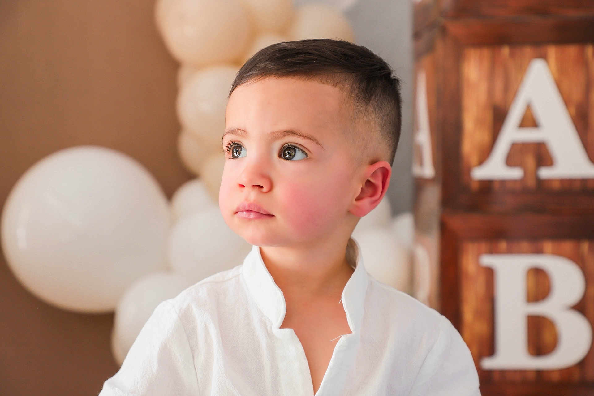 Gianluca joined the competition — help win amazing prizes! toddler, child, boy, portrait, face, white_shirt, balloons, wooden_blocks, letters, short_hair, indoors, soft_light, celebration, cute, innocence, looking_away, young_child, background_blur, casual_clothing, event