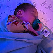 Leonidas joined the competition — help win amazing prizes! baby, sleeping, pacifier, blanket, crib, infant, child, bedtime, soft_light, cozy, clothing, hand, head, face, patterned_sheet, indoor, peaceful, rest, newborn, wrapped