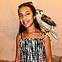Chaïnez a rejoint le concours — aidez-le/la à gagner de superbes lots ! girl, child, bird, falcon, animal, smile, portrait, shoulder, outdoor, evening, dress, patterned_clothing, young, person, nature, wildlife, pet, feathers, happy, closeup