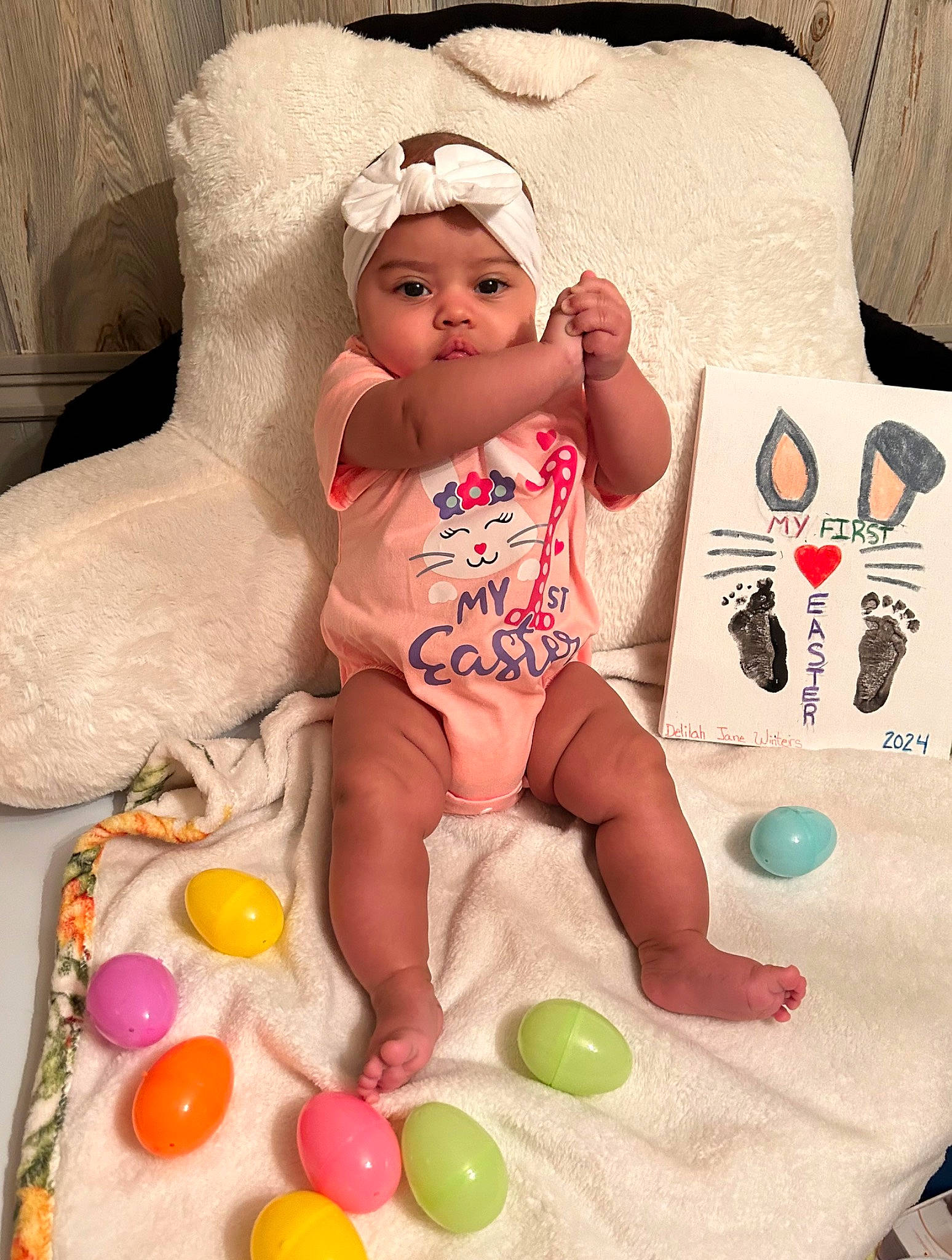 Delilah is registered to the contest to win money with this photo: abdomen, baby, baby_products, baby_toddler_clothing, chest, child, comfort, easter, easter_egg, event, foot, headwear, linens, party_supply, person, play, room, sitting, sweetness, textile