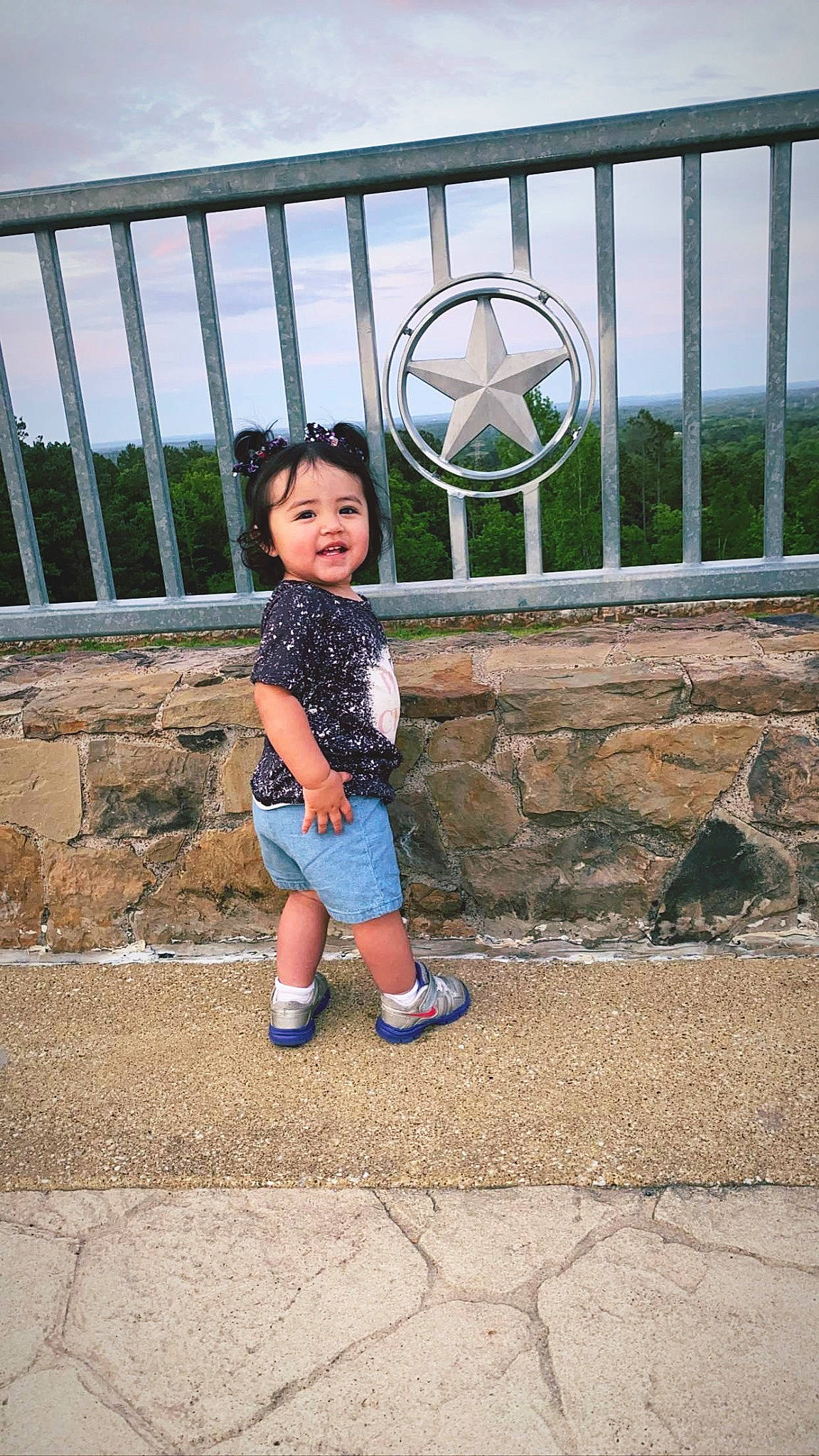 Dahlia is registered to the contest to win money with this photo: asphalt, child, electric_blue, fence, fun, happy, human_leg, leisure, line, pattern, person, road_surface, shorts, sitting, sky, smile, stairs, t_shirt, toddler, tourism