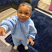 Raelynn joined the competition — help win amazing prizes! child, toddler, smiling, portrait, indoor, living_room, blue_outfit, hoodie, sweatpants, sneakers, rug, sofa, home, standing, reaching, curly_hair, hair_bun, earrings, floor, photography