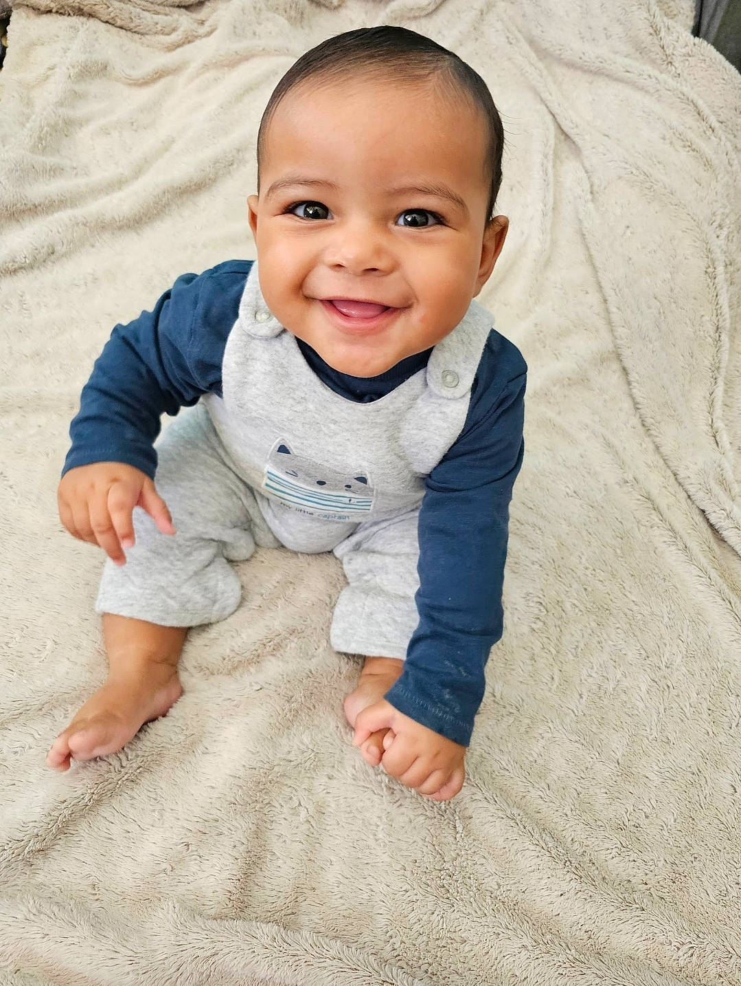 Elios participe au concours pour gagner de l'argent avec cette photo : baby, baby_toddler_clothing, cheek, child, comfort, eye, floor, flooring, fun, gesture, grass, happy, head, joy, linens, person, sitting, skin, sleeve, smile