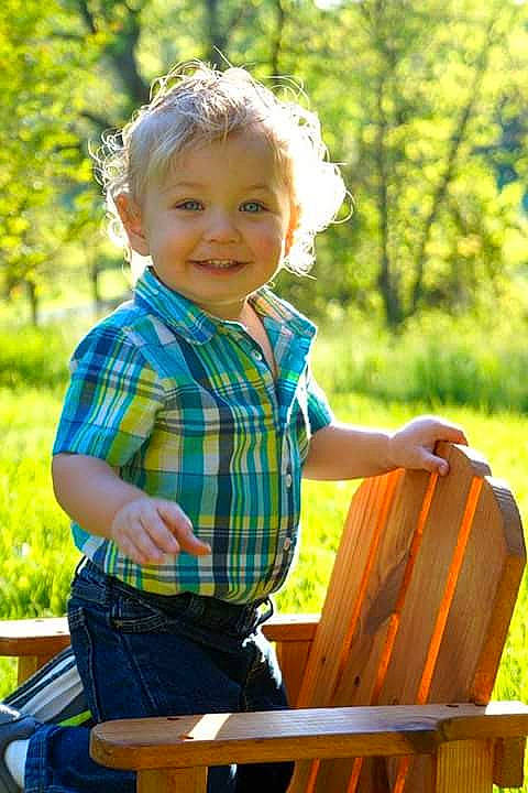 Houston is registered to the contest to win money with this photo: baby_toddler_clothing, facial_expression, fun, grass, happy, joy, leaf, leisure, light, people_in_nature, person, plaid, plant, smile, standing, summer, sunlight, t_shirt, tartan, toddler