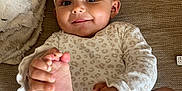 Alana is registered to the contest to win money with this photo: baby, infant, smiling, playful, headband, leopard_print, feet, hands, couch, blanket, clothing, happy, person, skin, indoors, cute, young_child, portrait, sitting, cozy