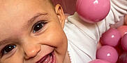 Alana is registered to the contest to win money with this photo: baby, smiling, child, face, pink, balls, ball_pit, white_clothing, happy, play, cute, infant, closeup, indoors, cheerful, skin, eyes, mouth, tongue, fun