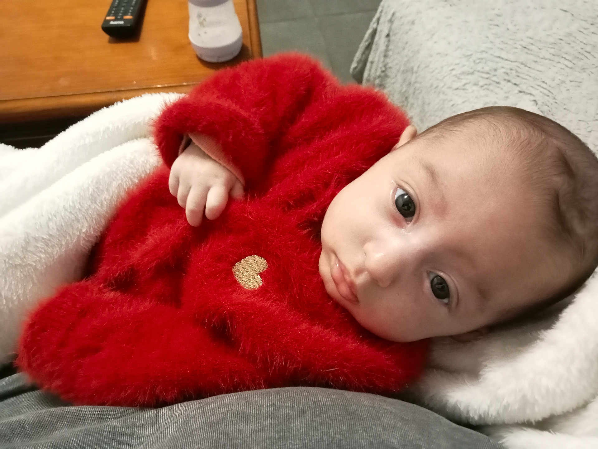 Rose a rejoint le concours — aidez-le/la à gagner de superbes lots ! baby, infant, red_sweater, fuzzy_clothing, blanket, white_blanket, face, eyes, hand, cute, cozy, indoors, portrait, newborn, skin, lying_down, warm_clothing, soft_texture, closeup, child