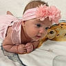 Loicy Lorenzo is registered to the contest to win money with this photo: baby, infant, child, portrait, pink_clothing, headband, flower, floral_accessory, blue_eyes, lying_down, tummy_time, smiling, curious, hands, earring, blanket, stuffed_animal, bed, indoors, closeup