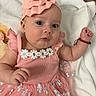 baby, infant, child, portrait, pink_outfit, dress, floral_pattern, headband, ruffles, blanket, lying_down, face, eyes, wide_eyed, hand, bracelet, earrings, indoor, close_up, cute