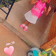Kemoni is registered to the contest to win money with this photo: child, girl, pink_clothing, white_skirt, backpack, peace_sign, braided_hair, beads, tricycle, porch, concrete, brick_wall, metal_railing, outdoor, smiling, filter, mouse_ears, tiara, heart_overlay, date_overlay
