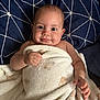 baby, blanket, bed, child, cute, face, infant, lying_down, patterned_bedspread, person, portrait, skin, soft_texture, wrapped, young_child, hand, eyes, smile, indoors, resting