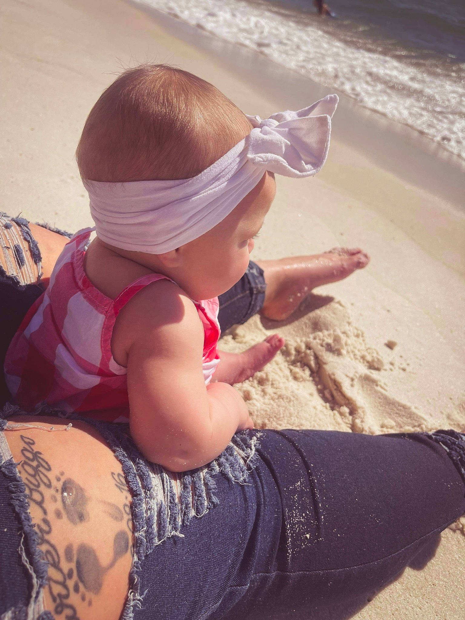 Gracelynn joined the competition — help win amazing prizes! baby, beach, body_of_water, cap, child, cool, fun, happy, hat, human_leg, leisure, people_in_nature, people_on_beach, person, sand, sitting, summer, sunlight, thigh, toddler