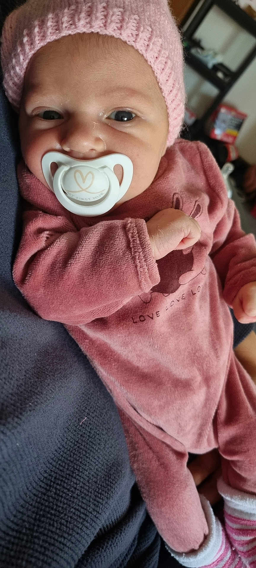 Talya participe au concours pour gagner de l'argent avec cette photo : baby, infant, pacifier, pink_hat, pink_clothing, knit_hat, soft_fabric, cuddly, cute, portrait, person, newborn, child, cozy, hand, striped_sock, indoor, closeup, resting, warm