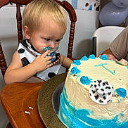 Kash is registered to the contest to win money with this photo: balloons, birthday_cake, blue_frosting, cake, celebration, child, clothing, cowboy_theme, curious, face, food, frosting, hand, indoor, messy_face, party_decoration, person, table, toddler, wooden_chair