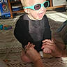 toddler, child, sunglasses, laughing, happy, indoor, rug, hands, adult, light, hair, black_clothing, living_room, furniture, television, toy, floor, pattern, person, playful