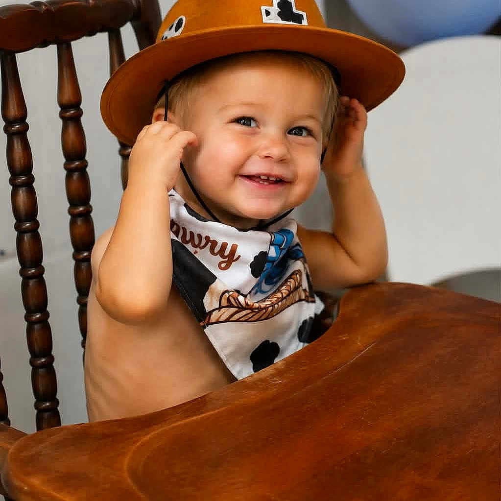 Kash is registered to the contest to win money with this photo: toddler, child, smiling, cowboy_hat, bandana, high_chair, wooden_chair, indoor, happy, portrait, baby, face, clothing, balloon, furniture, cute, sitting, expression, headwear, playful
