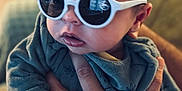 Leny a rejoint le concours — aidez-le/la à gagner de superbes lots ! baby, child, sunglasses, hand, person, portrait, indoor, clothing, blue_outfit, cute, infant, face, young, holding, fingers, closeup, soft_light, expression, casual, warm