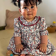 Aya joined the competition — help win amazing prizes! baby, toddler, child, floral_dress, pigtails, hair_bows, big_eyes, chubby_cheeks, smile, sitting, barefoot, wooden_toy, toy, portrait, indoor, cushion, playmat, hands, feet, adorable