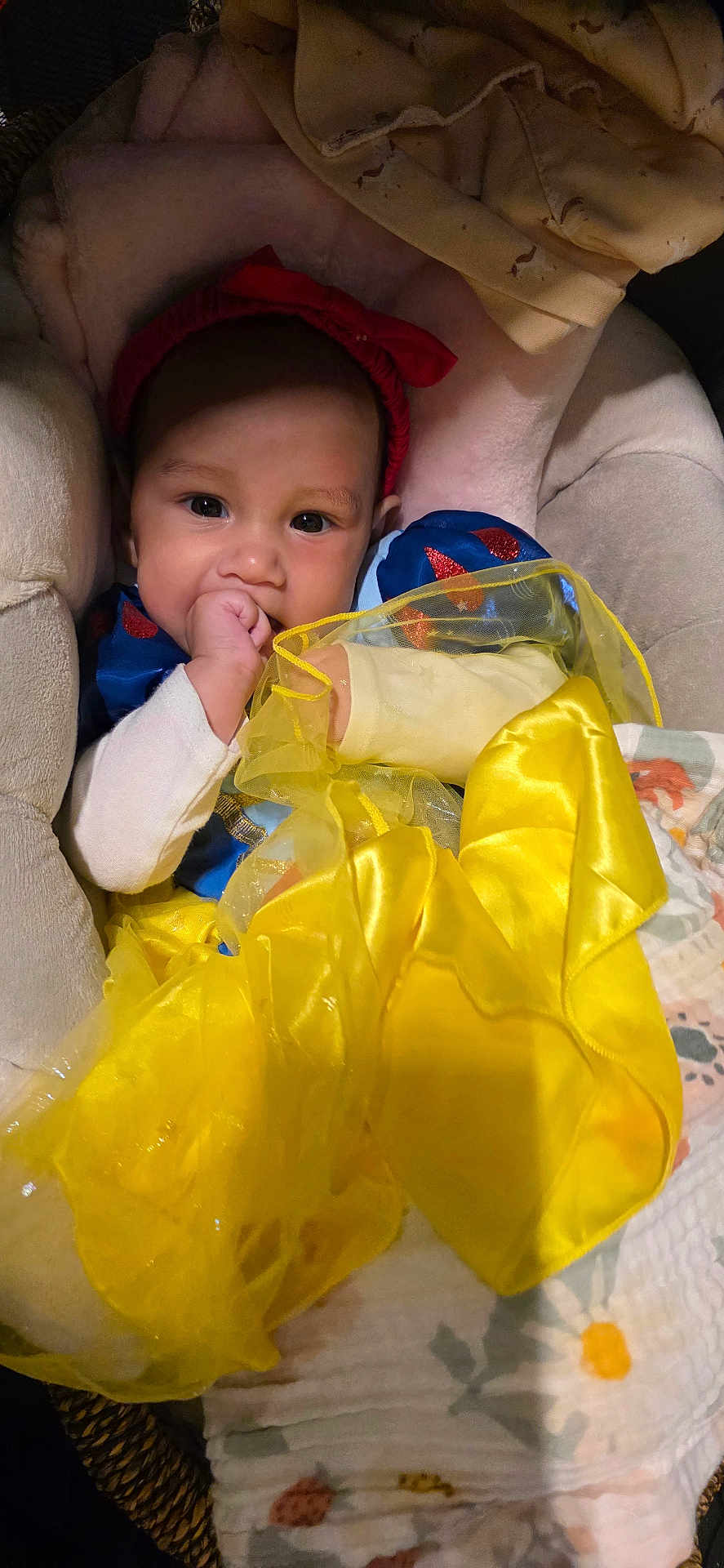Rinoa joined the competition — help win amazing prizes! baby, child, costume, dress, yellow, blue, red_headband, blanket, cushion, seat, indoors, cute, infant, sitting, thumb_sucking, person, fabric, soft, portrait, cozy