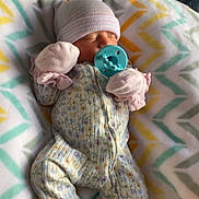 Hazel is registered to the contest to win money with this photo: newborn, baby, pacifier, blanket, mittens, hat, sleeping, onesie, floral_pattern, infant, cozy, bed, soft, child, cute, resting, warm, indoor, portrait, peaceful