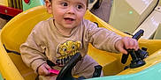 Tiago participe au concours pour gagner de l'argent avec cette photo : baby, carousel, child, colorful, happy, indoor, kiddie_ride, mall, parent, plastic, playing, portrait, reflection, seat, simba_print, smile, steering_wheel, sweatshirt, toddler, toy_car