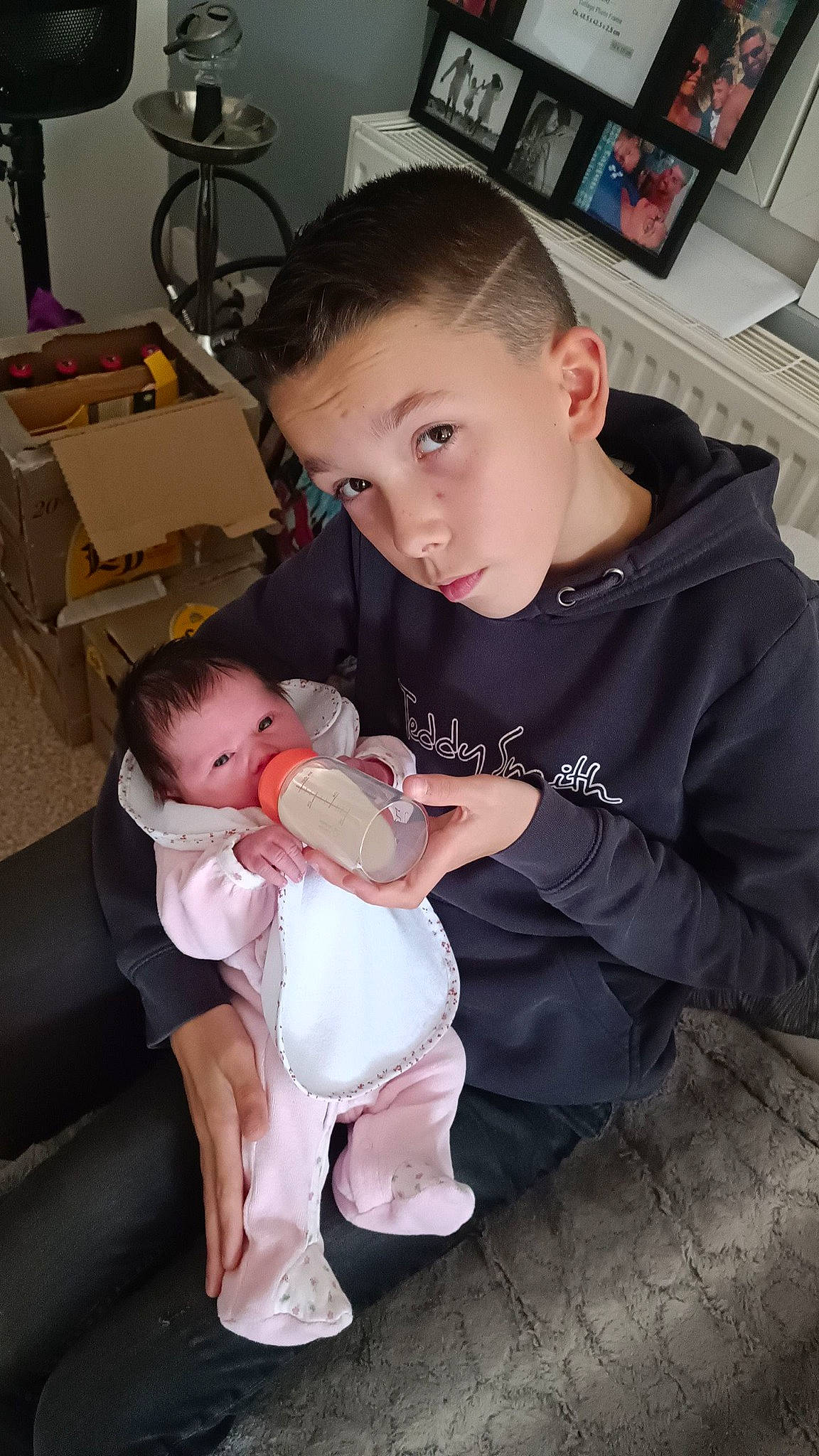 Mathéo a rejoint le concours — aidez-le/la à gagner de superbes lots ! abdomen, baby, baby_toddler_clothing, child, comfort, facial_expression, fun, hair, head, lap, leg, person, picture_frame, room, shelf, sitting, skin, t_shirt, thigh, toddler