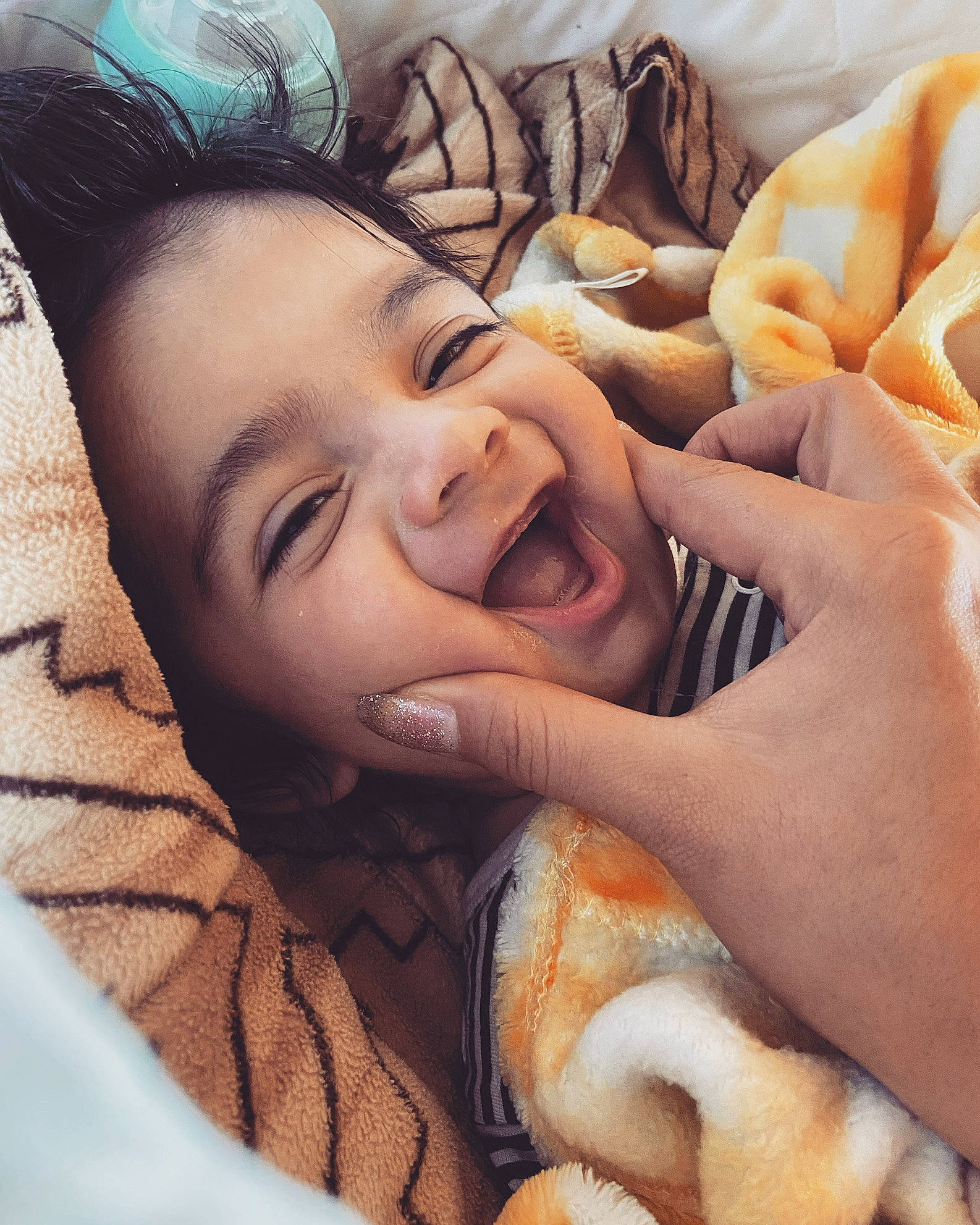 Solomon is registered to the contest to win money with this photo: baby, child, close_up, comfort, event, eyebrow, finger, fun, gesture, happy, laugh, linens, mouth, nail, nose, person, selfie, skin, smile, thumb