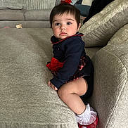 Isabella joined the competition — help win amazing prizes! baby, child, girl, couch, sofa, red_bow, red_shoes, white_socks, plaid_skirt, navy_top, living_room, cushion, soft_furniture, indoors, portrait, sitting, curious, cute, young_child, home