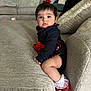 baby, child, girl, couch, sofa, red_bow, red_shoes, white_socks, plaid_skirt, navy_top, living_room, cushion, soft_furniture, indoors, portrait, sitting, curious, cute, young_child, home