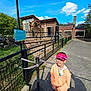 Valentin a rejoint le concours — aidez-le/la à gagner de superbes lots ! boy, child, cap, hoodie, jeans, outdoor, sunlight, fence, giraffe, animal, zoo, building, sky, cloud, grass, pathway, shadow, visitor, nature, daytime