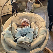Omari is registered to the contest to win money with this photo: newborn, baby, infant, sleeping, face, portrait, rocker, baby_gear, blanket, swaddled, hat, toy, dinosaur, nursery, indoor, home, fan, furniture, wood_floor, cozy