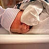 Omari is registered to the contest to win money with this photo: newborn, baby, sleeping, infant, face, portrait, blanket, swaddled, hat, striped_clothing, bedding, cozy, indoors, peaceful, resting, closed_eyes, snug, soft_lighting, nursery, nap