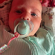 Esmae joined the competition — help win amazing prizes! baby, pacifier, infant, close_up, blanket, pink, mint_green, ribbed_fabric, face, eyes, mouth, clothing, laying_down, indoor, soft_light, cartoon_print, fabric, calm, person, newborn