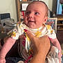 Esmae is registered to the contest to win money with this photo: baby, bee_pattern, blanket, bookshelf, clothing, comfort, cute, expression, face, furniture, hand, holding, indoor, infant, living_room, person, skin, smiling, star_pattern, television