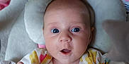 Esmae is registered to the contest to win money with this photo: baby, blue_eyes, child, closeup, clothing, colorful, cushion, cute, expression, face, floral_pattern, hand, happy, indoor, infant, newborn, person, seat, soft, toy
